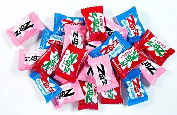 A pile of Zotz Fizz Power Candy Assorted - Fruit Flavored Hard Candy with a Fizzy Center | 230g Bag, Single Pack | Cherry, Watermelon & Blue Raspberry | Gluten-Frwe wrappers on a white surface.