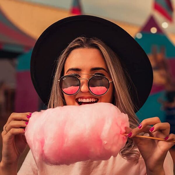 A woman holding a Jelly Belly Jelly Beans 3.5oz Cotton Candy at an amusement park.